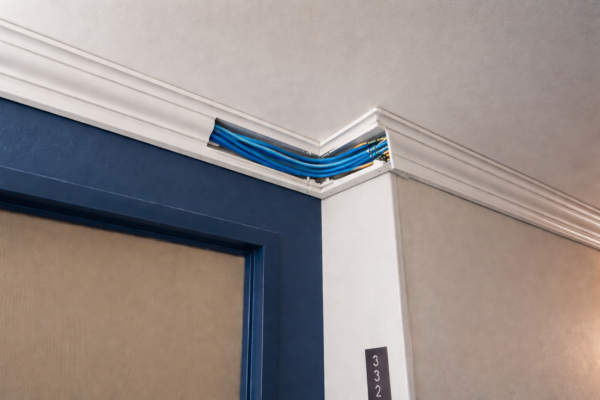 Crown Molding Raceway showing blue cables hidden and routed around the ceiling of a room.